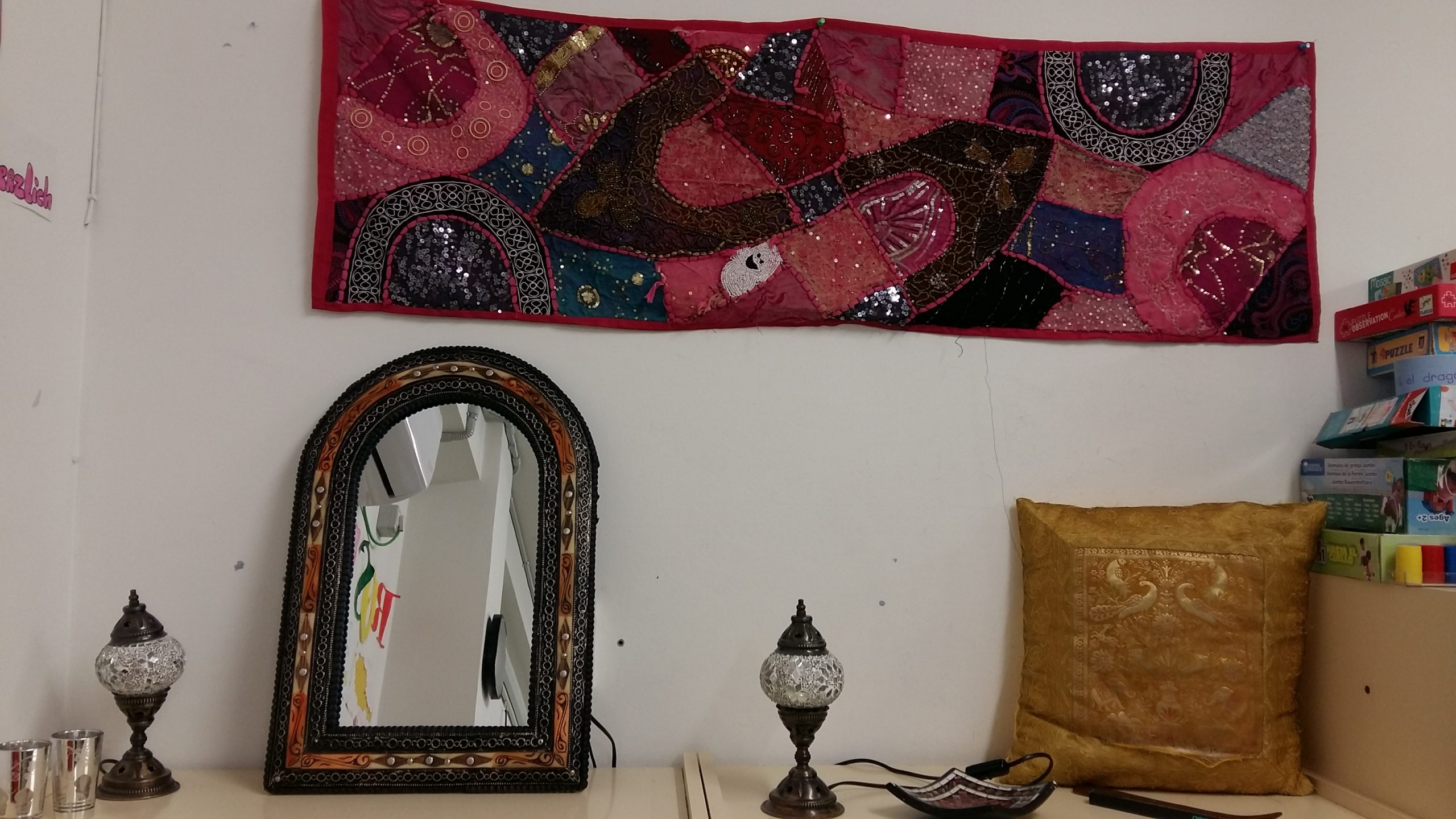 Fotografía del rincón de Marruecos que cuenta con un tapiz, un espejo, lámparas, cojines...