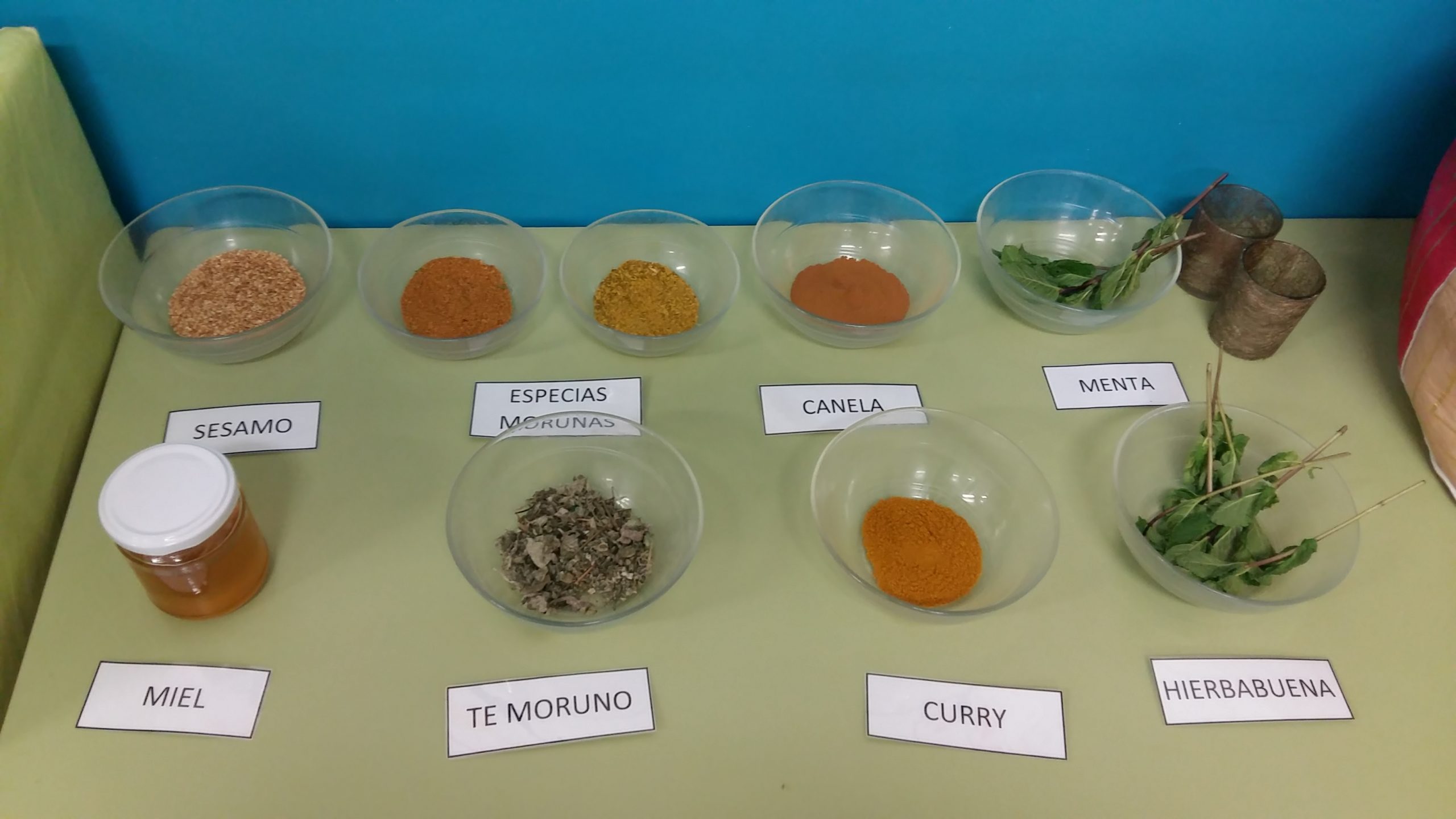 Fotografía de una mesa con distintas especias (especias morunas, canela, miel, curry...) y otros productos (miel, té moruno...)