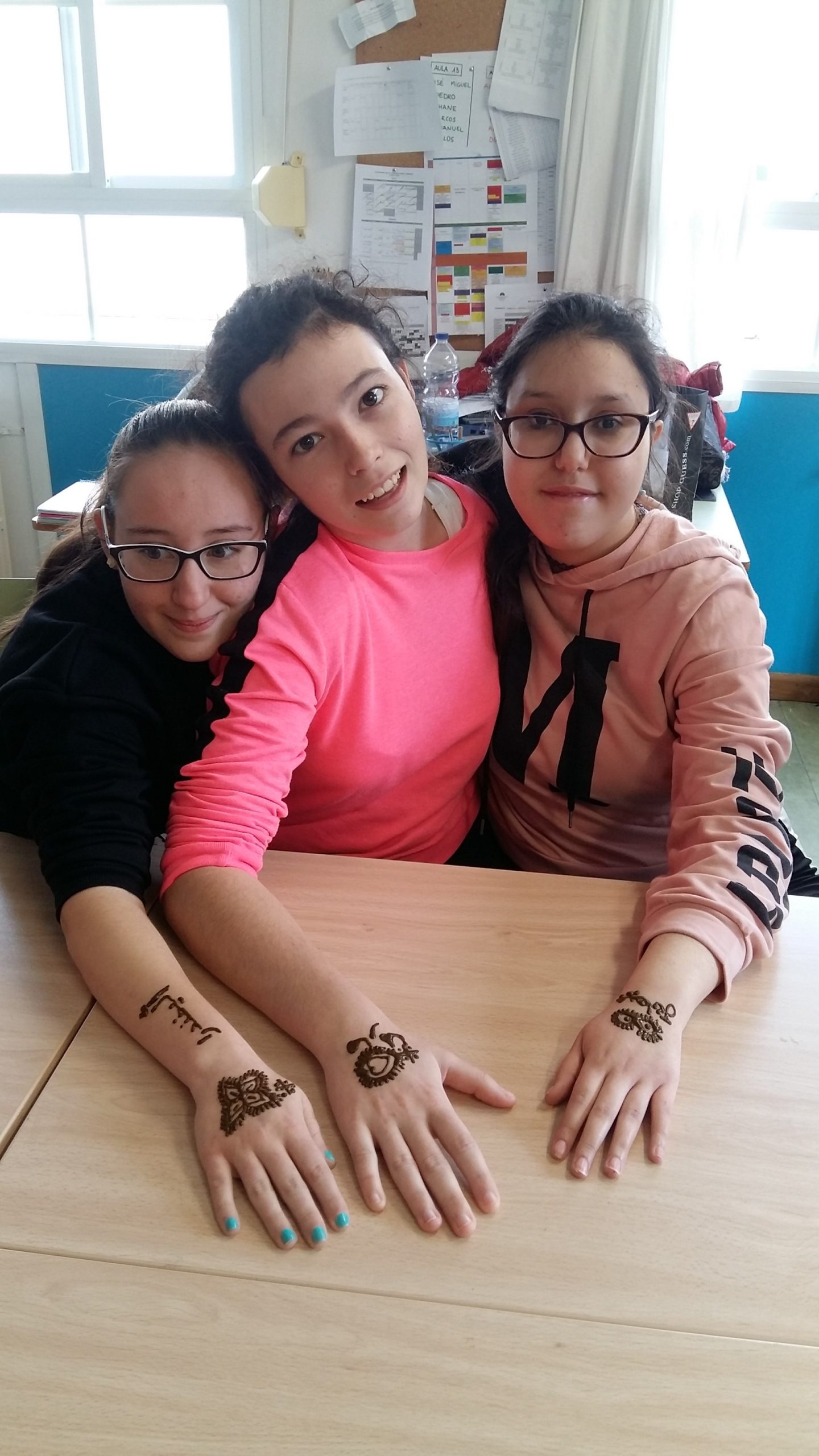 Tres alumnas mostrando los tatuajes de henna que les han hecho en la mano