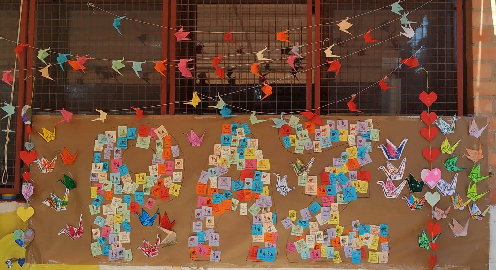Fotofrafía del mural de la paz que que incluye papeles con mensajes y grullas de origami